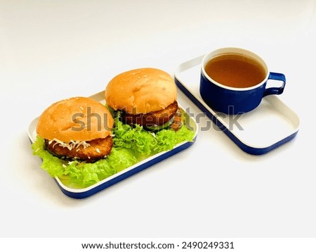 bread filled with lettuce, cucumber, bacon and cheese and a cup of warm ginger water. can be used for food display photos, articles, menu books and other editorial uses. with copy space.Chicken burger