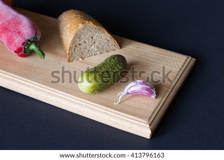 Bread, garlic pickles and red peppers on a black background
