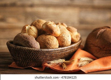 Bread and lots of fresh bread buns in a basket on a wooden table - Powered by Shutterstock