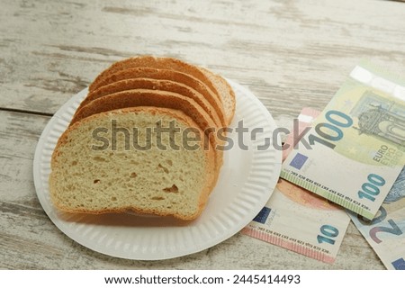 Bread on a plate on the table next to euro bills of different denominations, rising food prices in Europe