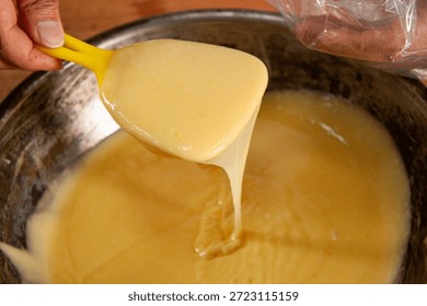 Bread and pastry making process: Close-up of a pastry chef piping sweet cream filling or preparing gourmet stuffing for artisanal bread and pastries.