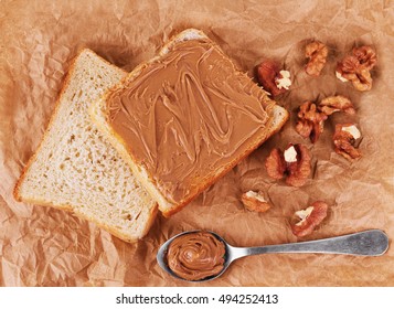 Bread With Peanutbutter, Walnuts And Spoon On A Paper Background