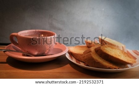 Bread is placed in a plate with coffee in a cup.