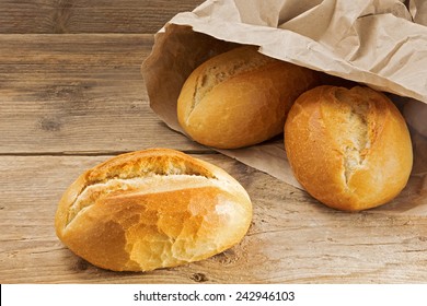 Bread Rolls In A Paper Bag On A Rustic Wooden Table, Fresh From The Bakery For Breakfast