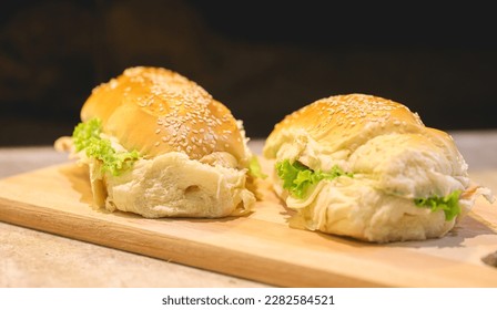 Bread sandwich with sesame seeds, turkey breast, mozzarella cheese, lettuce, tomato and seasoned mayonnaise. Wooden board.  - Shutterstock ID 2282584521