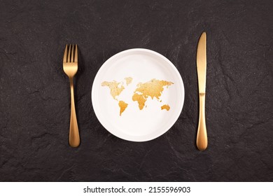Bread in shape world map on white plate. Gold fork and knife on a dark stone background. Abstract Concept of global hunger. - Shutterstock ID 2155596903