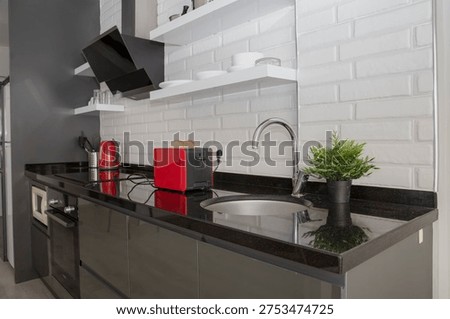 Bread slices inside red kitchen toaster on black countertop in modern home kitchen interior