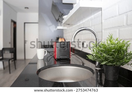 Bread slices inside red kitchen toaster on black countertop in modern home kitchen interior
