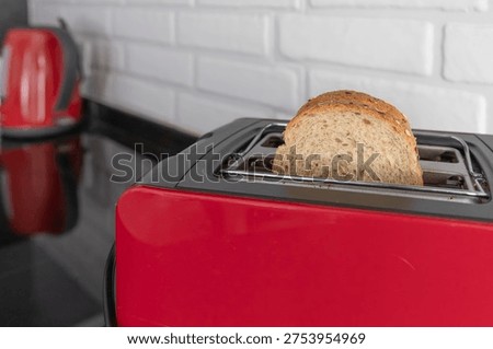 Bread slices inside red kitchen toaster on black countertop in modern home kitchen interior