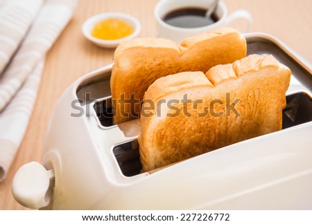 Bread slices in toaster with coffee and jam