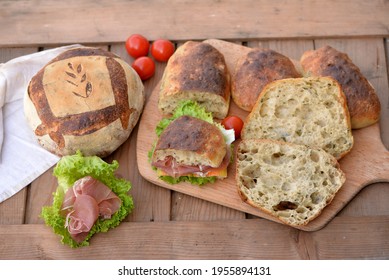 Bread Texture Of Ciabatta, Italian Flat Bread Cut In Half; Sandwich Bread Slices With Chopped Wild Garlic On Wooden Board, Smoked Ham And Cheese Sandwich, Garlic Bread Loaf And Buns In Background