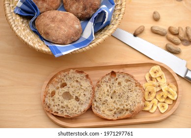 Bread Texture Of Ciabatta, Italian Flat Bread Cut In Half; Sandwich Bread Slices And Dry Banana Slices   On Wooden Board With Delicious Pita Breads In Breadbasket And Peanuts In Background
