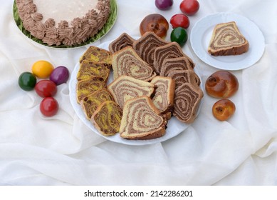 Bread Texture Of Easter Bread Slices. Assortment Of Easter Cakes: Walnut Roll, Pumpkin Swirl With Hazelnuts And Chocolate Roll With Carob; Chocolate Cake, Easter Eggs And Chicken Buns In Background.