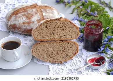 Bread texture of sliced dark bread loaf, cup of coffee and jam. Home baked wheat bread with rye flour and sesame seeds; two loafs of crusty sourdough wheat bread with rye flour; one loaf cut in half. - Shutterstock ID 2196382955