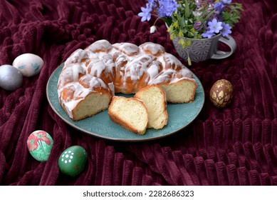 Bread texture of sliced Easter bread with sugar glaze in a shape of wreath with Easter eggs. Sweet bread sliced with Easter eggs and flowers. Home baked braided bread with two slices of Easter cake.