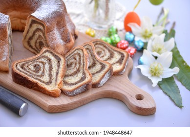 Bread Texture Of Slovenian Potica, Traditional Easter Cake With Walnut Filling; Sliced Sweet Easter Bread Roll On Wooden Board With Chocolate Eggs And Hellebores In Background