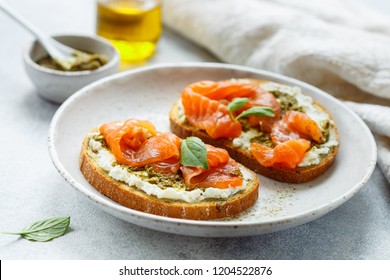 Bread toast with salted salmon, pesto sauce and cream cheese (ricotta). Gourmet snack. selective focus
