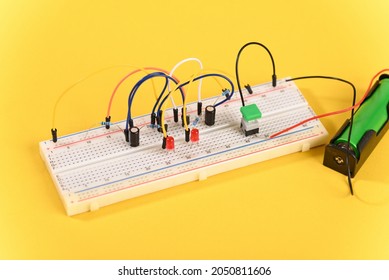 Breadboard with electrical elements, on yellow background.