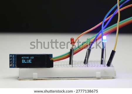 Breadboard electronics with blue LED glowing and message displayed on the OLED display