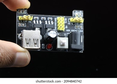 Breadboard power supply module held in hand isolated on black background