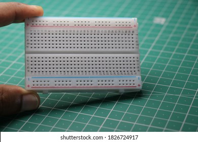 Breadboard which is used in solderless prototyping of various electronic projects held in hand having 400 points