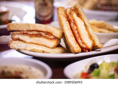 Breaded Chicken Breast Parmigiana Provolone And Mozzarella Cheese Toasted Sliced Artisan Sourdough Bread Panini On White Plate With French Fries And Salad