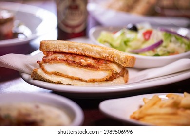 Breaded Chicken Breast Parmigiana Provolone And Mozzarella Cheese Toasted Sliced Artisan Sourdough Bread Panini On White Plate With French Fries And Salad