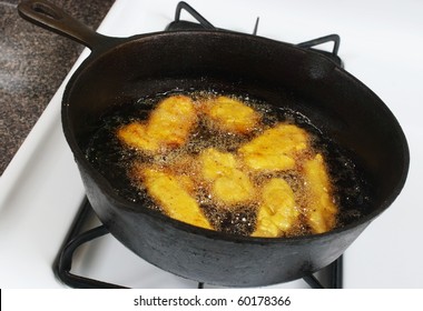 Breaded Chicken Deep Frying In Oil In A Cast Iron Frying Pan