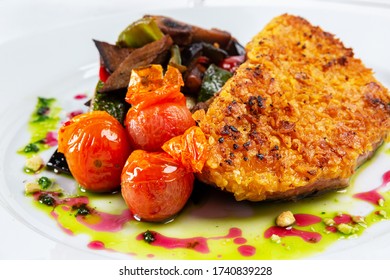 Breaded Chicken Filet, Accompanied By Cherry Tomatoes And Salad, Served On A White Plate Isolated Against A White Background.