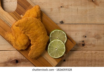 Breaded Chicken Filet With Lemon Slices, On A Wooden Background. Top Wiew