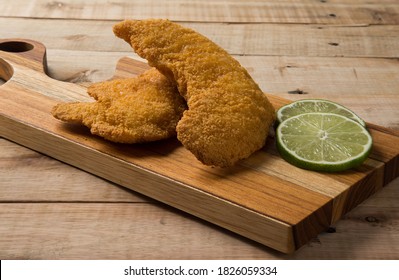 Breaded Chicken Filet With Lemon Slices, On A Wooden Background. Closeup
