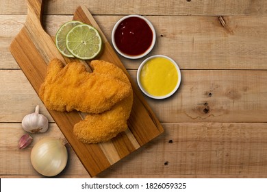 Breaded Chicken Filet, Served With Mustard And Ketchup, On A Wooden Background. Top Wiew