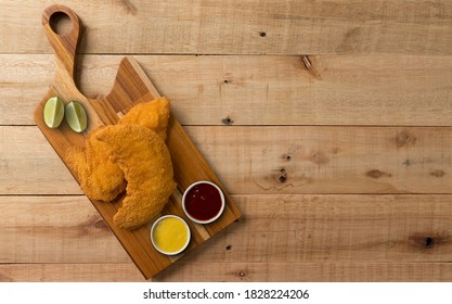 Breaded Chicken Filet, Served With Mustard And Ketchup, On A Wooden Background. Top Wiew