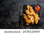 Breaded chicken strips  Fingers with  Ketchup. Black background. Top view. Copy space.