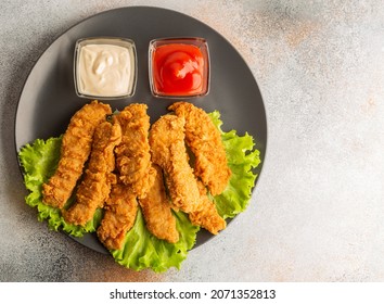 Breaded Chicken Strips With Two Kinds Of Sauces On Gray Plate. Fast Food On Gray Stone. Flat Lay. With Copy Space.