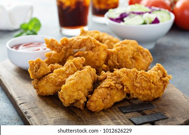 Breaded chicken tenders with ketchup, salad and soda - Shutterstock ID 1012626229