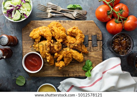 Breaded chicken tenders with ketchup, salad and soda