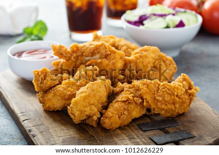 Breaded chicken tenders with ketchup, salad and soda