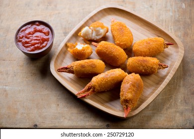 Breaded crab claws with dipping sauce over rustic wooden surface