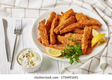 Breaded Fish Sticks, Fish Fillet Fingers Served On A White Plate On A Wooden Table With Tartar Sauce And Lemon Wedges, Landscape View From Above