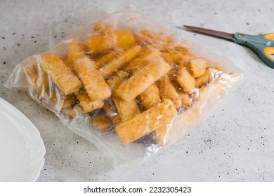 Breaded fish sticks frozen. Plastic bag of fish sticks in a crunchy golden breading close-up on the kitchen table - Shutterstock ID 2232305423
