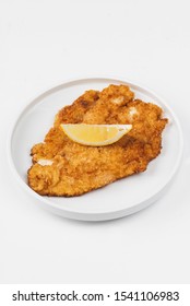 Breaded and fried chicken meat with lemon  in a plate on a white background