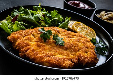 Breaded Fried Pork Chop And Fresh Vegetables On Black Table 