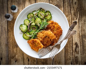 Breaded Fried Pork Chop With Sliced Cucumbers And Rosemary On Wooden Table 