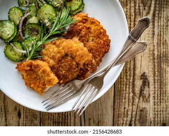 Breaded Fried Pork Chop With Sliced Cucumbers And Rosemary On Wooden Table 