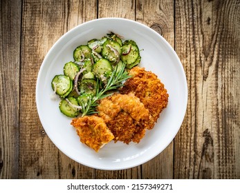 Breaded Fried Pork Chop With Sliced Cucumbers And Rosemary On Wooden Table 