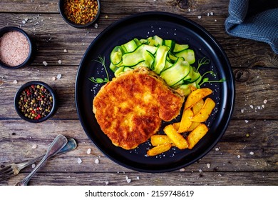 Breaded Fried Pork Chop With Sliced Cucumbers And French Fries On Wooden Table