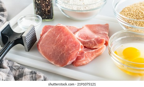 Breaded Pork Chops Recipe. Ingredients Close Up On Kitchen Table. Raw Pork Chops, Eggs, Flour, Bread Crumbs, Salt And Black Pepper