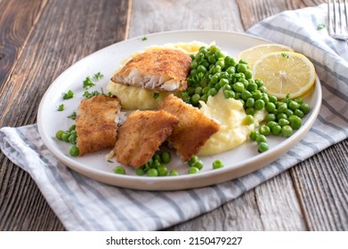 Breaded redfish with mashed potatoes and green peas on a plate