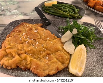 Breaded Veal Cutlet With A Side Of Arugula, String Beans And A Wedge Of Lemon.  Italian  Recipe. 